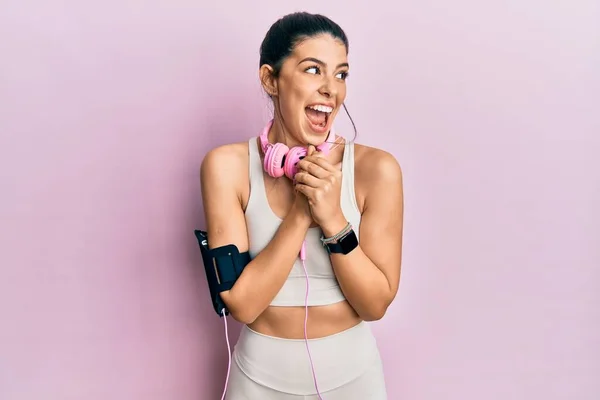 Young Hispanic Woman Wearing Gym Clothes Using Headphones Laughing Nervous — стоковое фото