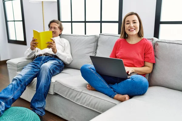中年男性と女性カップル読書本を使用してノートパソコンでホーム — ストック写真