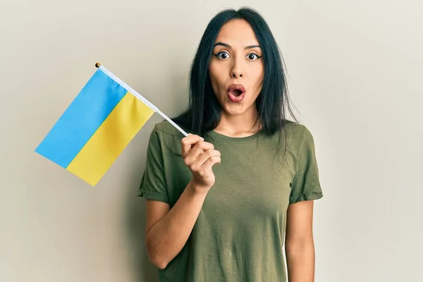 Young Hispanic Girl Wearing Ukraine Flag Scared Amazed Open Mouth — Stockfoto