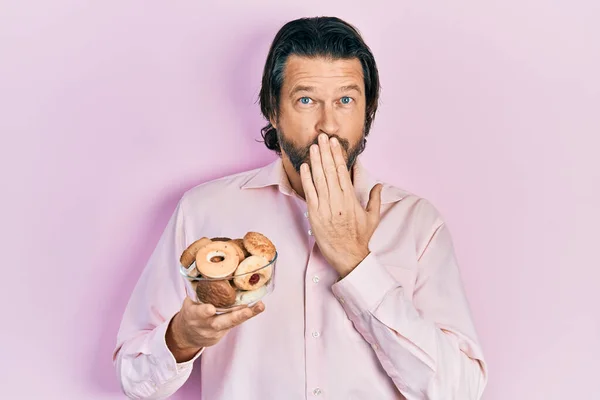 Middle Age Caucasian Man Holding Sweet Pastries Covering Mouth Hand — ストック写真