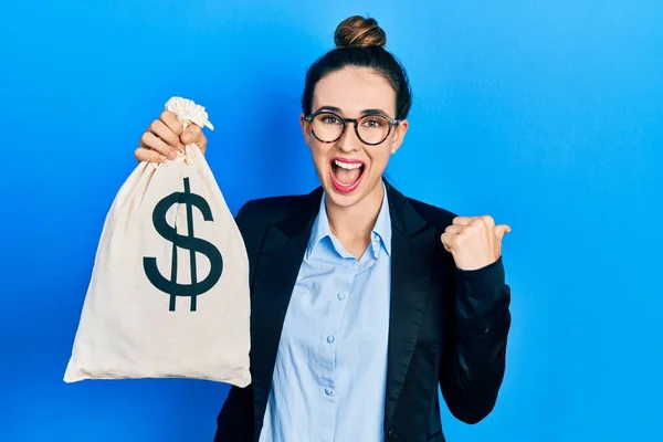 Young Hispanic Girl Wearing Business Clothes Holding Dollars Bag Pointing — 스톡 사진
