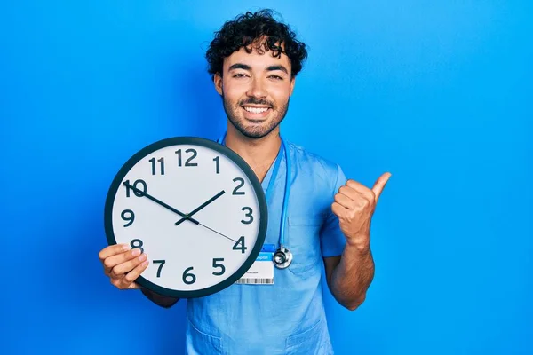 Young Hispanic Man Wearing Blue Male Nurse Uniform Holding Clock — Stok fotoğraf