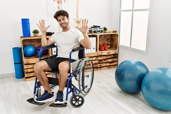 Hispanic Man Sitting Wheelchair Physiotherapy Clinic Showing Pointing Fingers Number — Stok fotoğraf