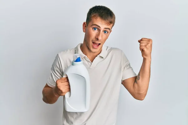 Νεαρός Καυκάσιος Άντρας Κρατάει Ένα Μπουκάλι Απορρυπαντικού Ουρλιάζοντας Περήφανος Γιορτάζοντας — Φωτογραφία Αρχείου