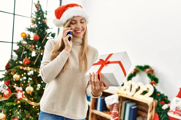 Young Blonde Woman Talking Smartphone Holding Christmas Gift Home — Φωτογραφία Αρχείου