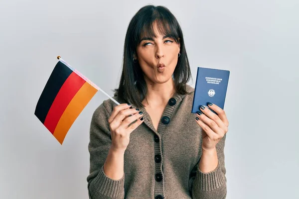 Young Hispanic Woman Holding Germany Flag Passport Making Fish Face — Stok fotoğraf
