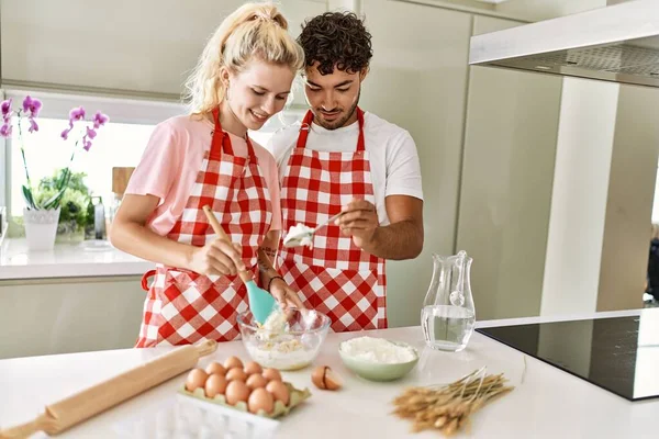 Pareja Joven Sonriendo Feliz Mezclando Ingredientes Para Hacer Masa Para —  Fotos de Stock