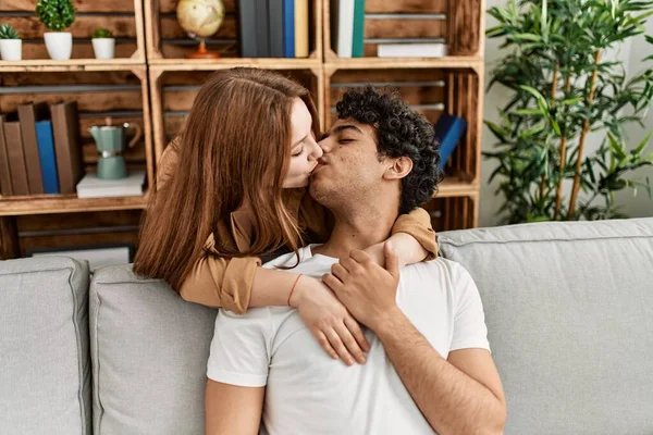 年轻夫妇坐在家里的沙发上亲吻和拥抱 — 图库照片