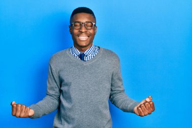 Young african american man wearing business style and glasses very happy and excited doing winner gesture with arms raised, smiling and screaming for success. celebration concept. 