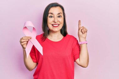 Orta yaşlı İspanyol kadın elinde pembe kanser kurdelesi tutarken bir fikir ya da soruyla şaşırdı. 