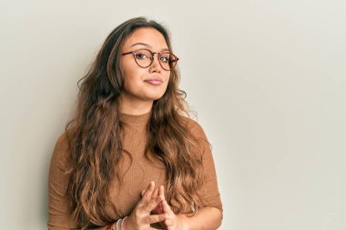 Gündelik kıyafetler ve gözlük takan genç İspanyol kız ellerini birleştirip gülümseyerek gevşemiş ve neşeliydi. Başarı ve iyimserlik 