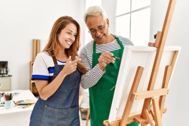 Orta yaşlı resim öğretmeni ve resim stüdyosunda gülümseyen mutlu bir öğrenci..