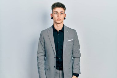 Young caucasian boy with ears dilation wearing business jacket relaxed with serious expression on face. simple and natural looking at the camera. 