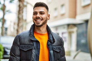 Yakışıklı, sakallı, neşeli ve kendine güvenen, kışlık palto giyen bir İspanyol.