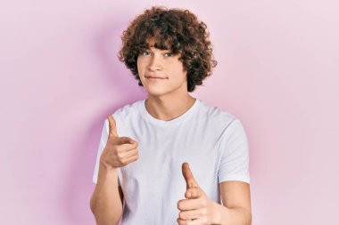 Handsome young man wearing casual white t shirt pointing fingers to camera with happy and funny face. good energy and vibes. 