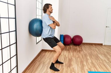 Orta yaşlı beyaz adam spor merkezinde formda top kullanıyor.