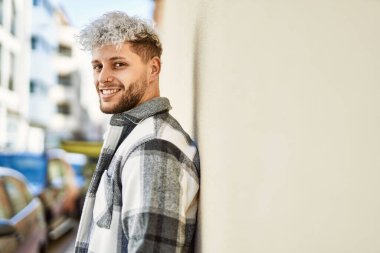 Genç İspanyol adam gülümseyerek şehirde mutlu mesut dikiliyor..