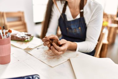 Beyaz bir kadın sanat stüdyosunda el yapımı kil çömlek yapıyor.