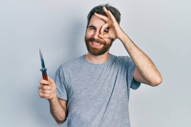 Sakallı, elinde çakı olan beyaz bir adam gülümsüyor. Mutluluktan gülümsüyor. 