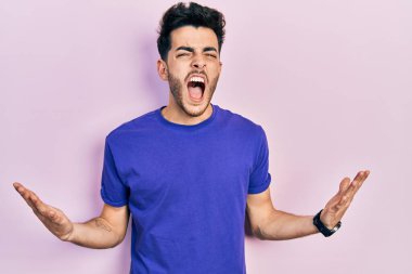 Gündelik tişört giyen genç İspanyol adam başarı için deli ve çılgınlığı kutluyor kollarını kaldırmış ve gözlerini kapatmış heyecanla bağırıyor. Kazanan konsept 