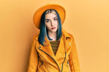 Young modern girl wearing yellow hat and leather jacket looking sleepy and tired, exhausted for fatigue and hangover, lazy eyes in the morning. 