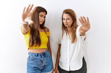 Mother and daughter together standing together over isolated background doing frame using hands palms and fingers, camera perspective 