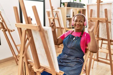Sanat stüdyosunda müzik dinleyen kıdemli Afro-Amerikan kadın.