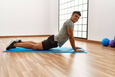 Genç İspanyol adam gülümsüyor spor merkezinde esniyor.