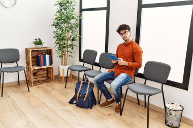 Genç İspanyol adam bekleme odasında dokunmatik ped kullanıyor.