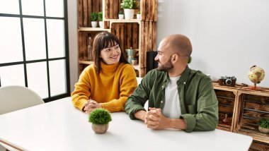 Genç İspanyol çift mutlu bir şekilde gülümsüyor. Evdeki masada oturuyorlar..