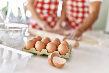 Mutfakta elleri ile hamuru yoğurmaktan mutlu gülümseyen genç çift..