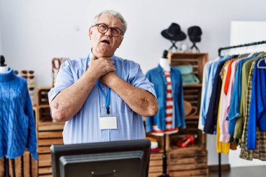 Senior man with grey hair working as manager at retail boutique shouting and suffocate because painful strangle. health problem. asphyxiate and suicide concept. 