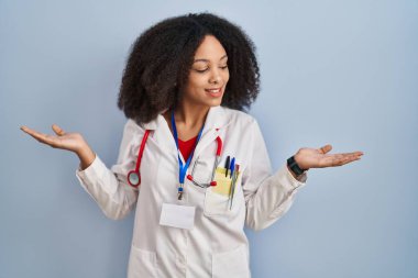 Doktor üniforması ve steteskop giymiş genç Afro-Amerikan bir kadın gülümseyerek avuçlarını açık gösteriyor, sunuyor ve reklam karşılaştırması yapıyor ve dengeyi sağlıyor. 