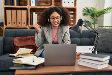 Young african american woman doing online session at consultation office screaming proud, celebrating victory and success very excited with raised arm 