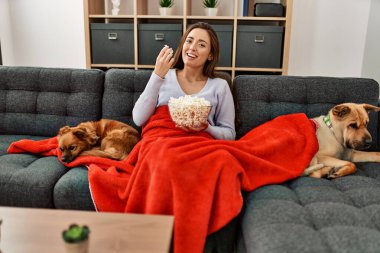 Genç İspanyol kadın evde köpeklerle kanepede oturup film izliyor.