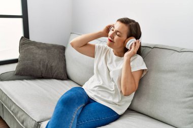 Orta yaşlı İspanyol kadın evde müzik dinliyor.