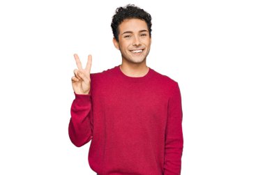 Gündelik kıyafetler giymiş genç yakışıklı adam kameraya bakıp zafer işareti yapıyor. İki numara.. 