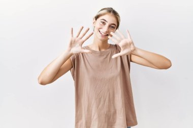 Young blonde woman standing over isolated background showing and pointing up with fingers number ten while smiling confident and happy. 