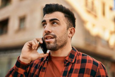 Genç İspanyol adam gülümsüyor. Şehirdeki akıllı telefondan konuşuyor..