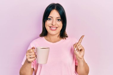 Genç İspanyol kadın bir fincan kahve içiyor. Gülümsüyor, mutlu bir şekilde elini ve parmağını yana uzatıyordu. 