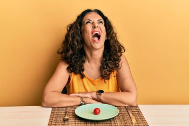 Beautiful middle age woman on a diet angry and mad screaming frustrated and furious, shouting with anger looking up. 