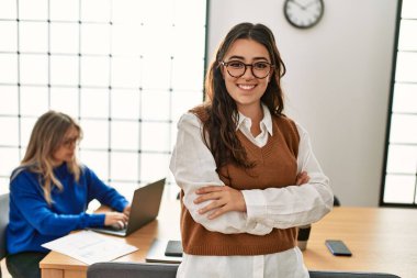 İş kadını kollarını kavuşturup mutlu bir şekilde gülümsüyor..