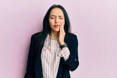 İş kıyafetleri giyen genç İspanyol kız diş ağrısı ya da diş hastalığından dolayı acı dolu bir ifadeyle ağıza dokunuyor. dişçi 