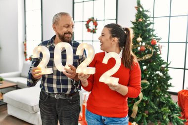 Genç kız ve büyük baba birlikte evde Noel 'i kutluyor, 2022 yılbaşı rakamlarını tutuyor.