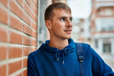 Üniversitede mutlu bir şekilde gülümseyen genç sarışın öğrenci..