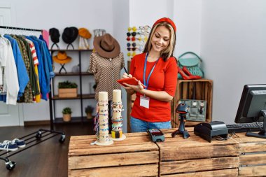 Genç beyaz kadın giyim mağazasında dokunmatik ped kullanıyor..