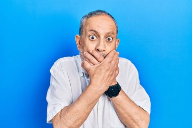 Handsome senior man with beard wearing casual white shirt shocked covering mouth with hands for mistake. secret concept. 