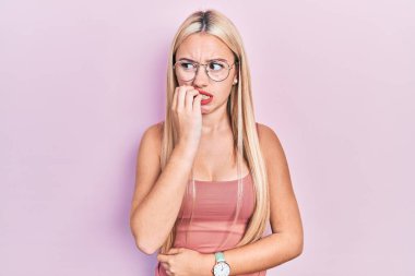 Günlük kıyafetler giyen genç sarışın kız gergin ve gergin görünüyor. Ağzı tırnak yiyen ellerle. anksiyete. 