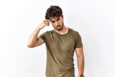 Hispanic man standing over isolated white background pointing unhappy to pimple on forehead, ugly infection of blackhead. acne and skin problem 