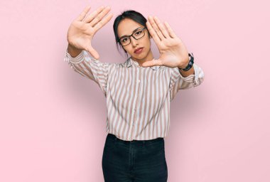 Gündelik kıyafetler ve gözlük takan, el ve parmaklarını kullanarak çerçeve yapan genç İspanyol kız, kamera bakış açısı. 